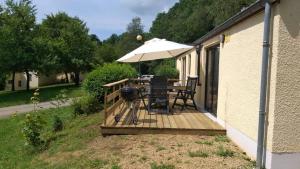 a wooden deck with a grill and an umbrella at Bungalows du Lac de Rabais in Virton
