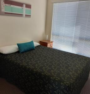 a bedroom with a bed with a blue pillow on it at Emerald Motel Apartments in Emerald