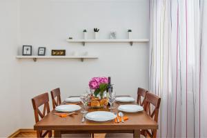 a wooden table with chairs and plates and flowers on it at Waikiki Beach House in Tivat