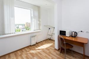 a room with a desk with a microwave and a window at Apartments at Yemelyanova 35а in Yuzhno-Sakhalinsk