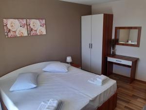 a bedroom with a large white bed and a mirror at Villa Ravlic in Podgora
