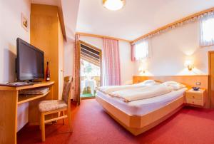 ein Schlafzimmer mit einem großen Bett und einem TV in der Unterkunft Pension Lafod in Dorf Tirol