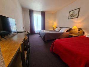 a hotel room with two beds and a flat screen tv at Hôtel Le Montaigu in Luz-Saint-Sauveur