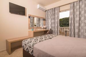 a bedroom with a bed and a desk and a window at Hotel Petros in Tsilivi