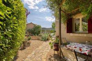 a patio with a table and chairs in a yard at Le Mas de la Noria in La Cadière-dʼAzur