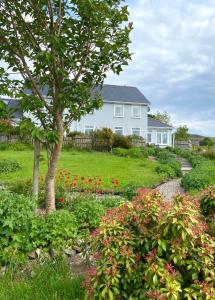 una casa con un árbol y flores en un patio en Brook Lodge en Glenties