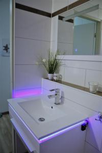 een badkamer met een witte wastafel met paarse verlichting bij Ferienwohnung Gold-Klee in Hahnenklee-Bockswiese