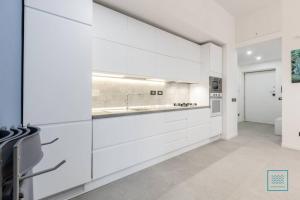 une cuisine avec des armoires blanches et un évier dans l'établissement Appartamento incantevole Lido di Ostia- Corallo Azzurro, à Lido di Ostia