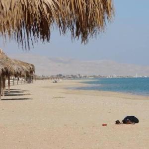 a person laying on a beach next to the water at Marina Wadi Degla - A Ground Chalet with 360 Garden in Ain Sokhna in Ain Sokhna