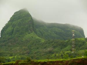 a misty mountain with a pole in front of it at Green Fog Guesthouse in Lonavala