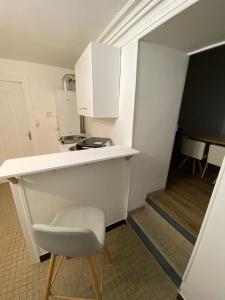 une petite cuisine avec un comptoir blanc et une chaise dans l'établissement Studios des Remparts - Avallon, à Avallon