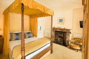 a bedroom with a four poster bed and a fireplace at Springkell in Eaglesfield