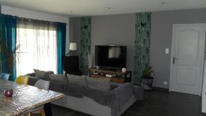a living room with a couch and a tv at Maison moderne à Cheval-Blanc in Cheval-Blanc