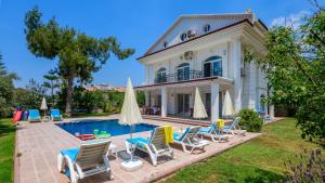 a villa with a swimming pool and chairs at Musa - 5 Bedroom Holiday Villa in Hisaronu in Fethiye