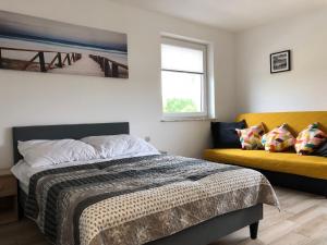 sypialnia z łóżkiem i żółtą kanapą w obiekcie Pokoje nad Morzem w Sztutowie