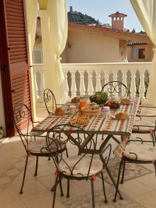 einen Tisch und Stühle auf einem Balkon mit Essen drauf in der Unterkunft B&B La Collina in Posada