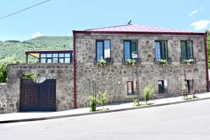 ein Steinhaus mit einer Holztür und Fenstern in der Unterkunft REDROOF country house hotel in Goris