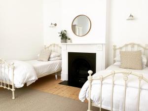 two beds in a room with a mirror and a fireplace at Castlebar - Superior Boutique Accomodation - Steps to Pakington Street in Geelong West