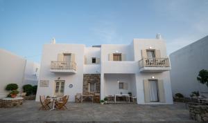 un edificio blanco con mesas y sillas delante en TWINS-TRISA APARTMENTS en Ornos