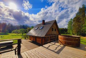 a large wooden cabin on a deck with a bench at Purgaiļi in Smiltene +13 photos