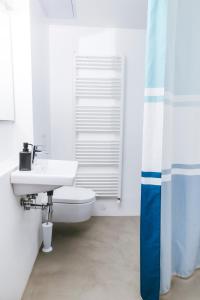 uma casa de banho branca com um lavatório e um WC em M9 Rooms em Izola