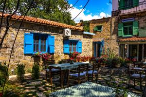 a house with blue shutters and a table and chairs at Adatepe Otel in Adatepe