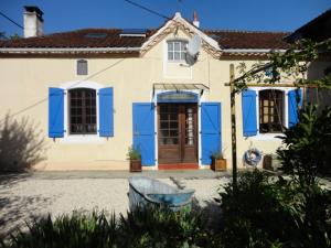 Viella Vacances في Viella: منزل بأبواب زرقاء ومقعد أمامه