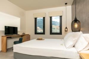 a bedroom with a large white bed and windows at Marajo Suites in Skala Potamias