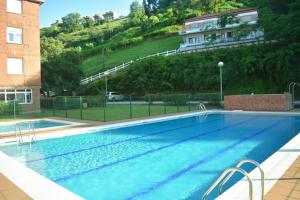 a large swimming pool in front of a building at Dos habitaciones Coqueto y cómodo apartamento con piscina y padel in Suances