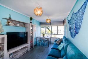 a living room with a blue couch and a television at Dos habitaciones Coqueto y cómodo apartamento con piscina y padel in Suances