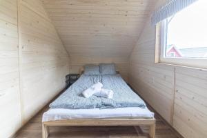 Cama en habitación pequeña con ventana en Domki Lena Kopalino en Kopalino