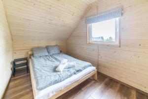 Cama en habitación de madera con ventana en Domki Lena Kopalino, en Kopalino