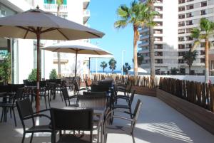 un patio con mesas, sillas y sombrillas en Hotel Santamarta, en Cullera