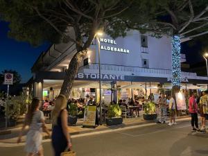 un grupo de personas caminando delante de una tienda en Hotel Aldebaran en Lido di Jesolo