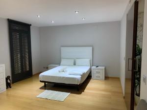 a white bedroom with a bed and a wooden floor at Luxury Apartment Mercat Central in Tarragona