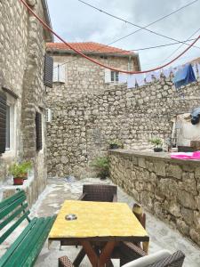 a patio with a table and chairs and a stone wall at Apartment Njegoš in Perast