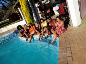 a group of people sitting on the edge of a swimming pool at SimbaSun Cottages in Midrand