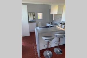 a kitchen with a counter and two stools at Petite maison de charme - Le jardin secret d'Alice in Roquebrune-sur-Argens +13 photos