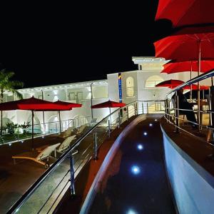 a swimming pool with red umbrellas on a cruise ship at Ganimede Hotel in Sperlonga