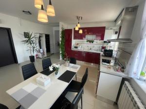 a kitchen with red cabinets and a white table and chairs at DreamView Mamaia SummerApt in Mamaia