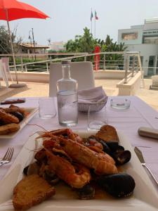 a table with a plate of seafood and a bottle of water at Ganimede Hotel in Sperlonga