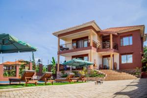 une maison avec des chaises et des parasols devant elle dans l'établissement Savannah Suites, à Kampala