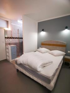 1 dormitorio con 1 cama grande con sábanas y almohadas blancas en Gites les 3 A, en Saint-Martin-de-Valamas