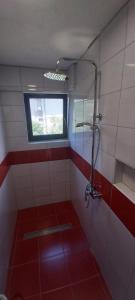 a bathroom with a shower with a window and red tiles at Apartman Nadija in Jajce