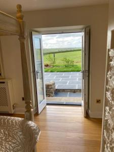 a bedroom with a door open to a patio at Snowdrop cottage @ Ty-llwyd in Treffynnon 