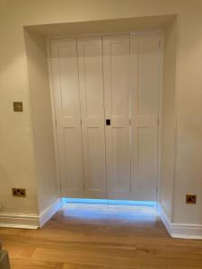 Cette chambre dispose de parquet et d'un placard avec des portes blanches. dans l'établissement Snowdrop cottage @ Ty-llwyd, à Treffynnon 