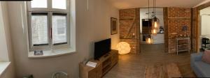 a living room with a tv and a brick wall at Warendorf 14 in Warendorf