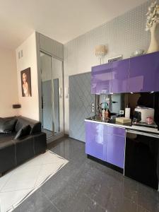 a kitchen with purple cabinets and a couch in a room at Belle Apartaments in Międzyzdroje