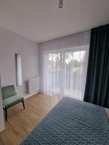 a bedroom with a bed and a chair and a window at Apartament na Wydmach Międzywodzie in Międzywodzie