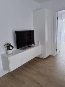 a living room with a tv on a white cabinet at Apartament na Wydmach Międzywodzie in Międzywodzie